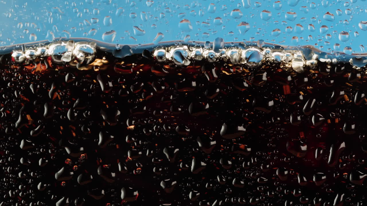 Close-up view of a cold soda drink with water droplets on the glass
