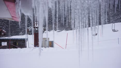 Snow-field-and-Ski-Lift-on-Winter-Day,-Icicles-in-Foreground