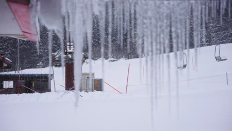 campo de nieve y remonte en día de invierno, carámbanos en primer plano