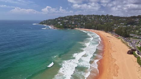 Aerial-over-the-beach-goers-golden-sand-and-surf-of-Palm-Beach-towards-the-headland