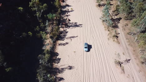 Antenne,-Offroad-Auto,-Das-Auf-Trockenem,-Sandigem-Flussbett-In-Abgelegenem-Buschland-Fährt,-Nach-Unten-Kippen