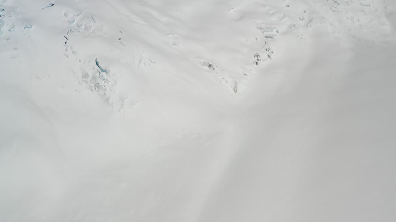 4K drone footage flying forward and panning up from glacier with crevasses to massive imposing mountains with icefalls