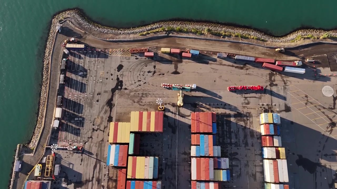 Industrial port in Wellington, New Zealand. The 4K video shows colorful shipping containers, trucks, and coastal export logistics