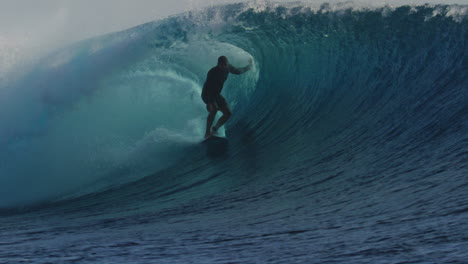 Surfer-balances-and-drags-wave-as-they-ride-deep-in-the-barrel-underneath-the-lip-of-wave,-Cloudbreak-Fiji