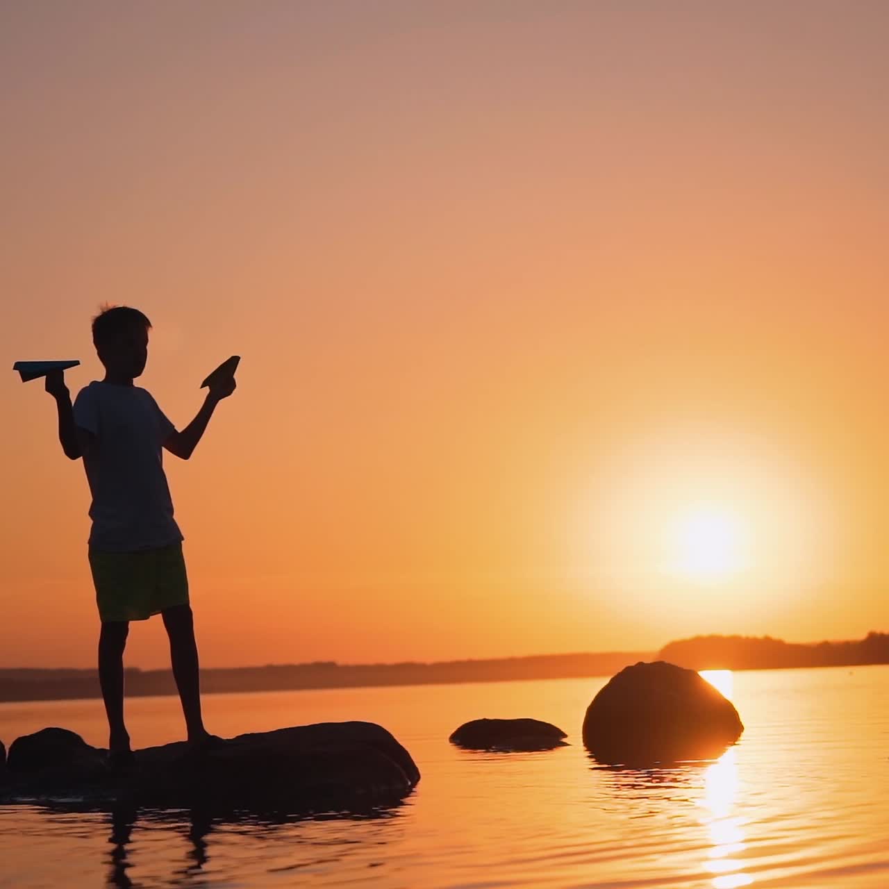 The boy throws a paper airplane. Beautiful sunset. Origami.