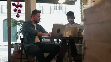 multiethnic freelancers using laptops in coffee shop