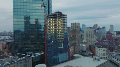 Tiro-Hacia-Atrás-Del-Sitio-De-Construcción-De-Edificios-Altos.-Grúa-Torre-Reveladora-Y-Rascacielos-Moderno-De-Gran-Altura-Con-Fachada-Brillante.-Boston,-Estados-Unidos