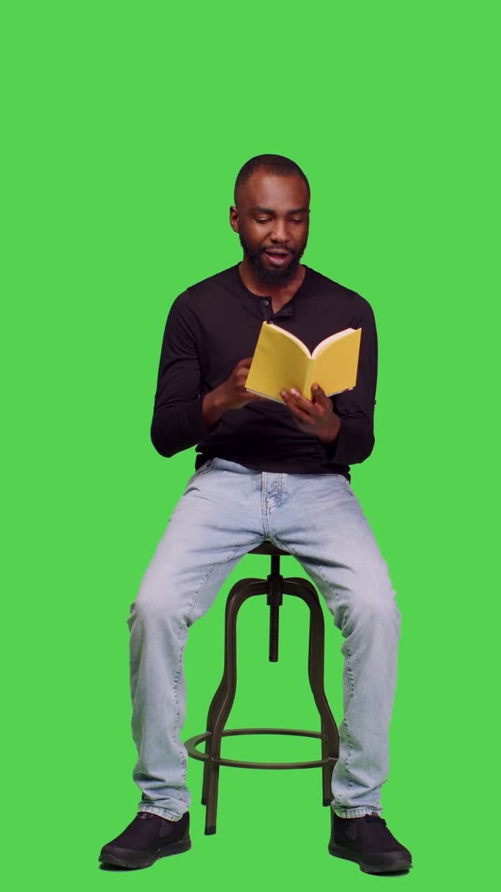 Vertical video: Front view of male model reading novel story on book in studio