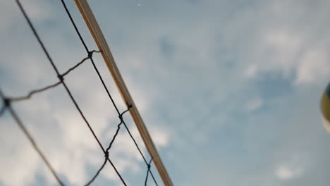 primer plano de una red de voleibol con la pelota jugando sobre ella, bajo un cielo brillante, capturando un momento emocionante en un juego de voleibal al aire libre con un hermoso telón de fondo natural