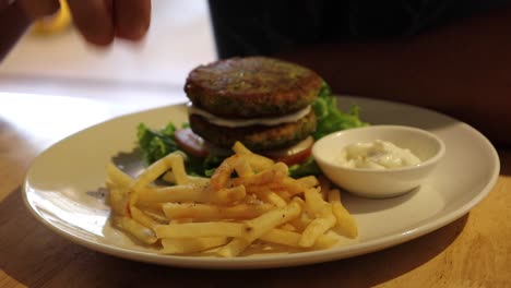 eating french fries and a falafel burger with vegan mayo, a pure plant based meal that is both healthy and cruelty free