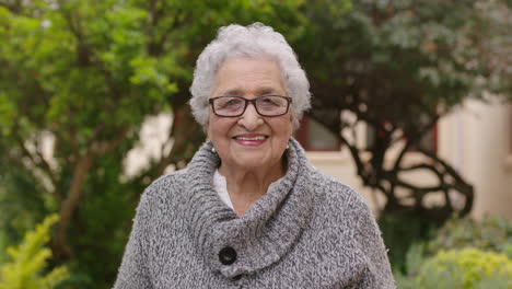 portrait of frail elderly woman in garden smiling happy wearing jumper