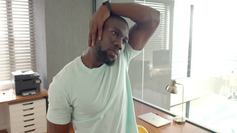 stretching neck muscles, man relaxing in home office with laptop on desk
