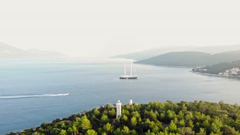 Vista-Panorámica-Sobre-El-Idílico-Paisaje-Marino,-El-Yate-Y-El-Faro-De-Fiskardo-En-Kefalonia,-Grecia---Tiro-Con-Drones