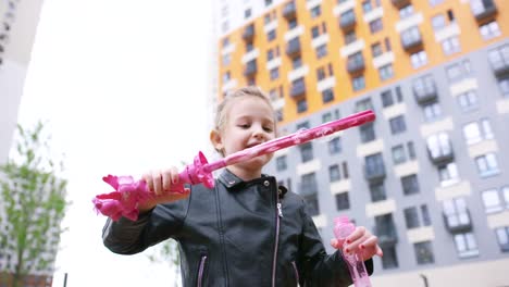 girl blowing bubbles in front of apartment building