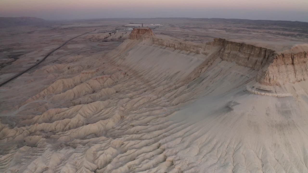 Aerial view of a desert cliff face at sunrise/sunset.