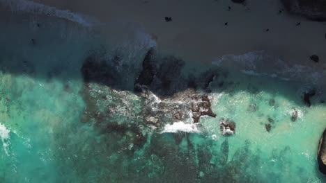 Vista-Aérea-De-Las-Olas-De-Agua-Azul-Cristalina-Que-Golpean-La-Costa-De-La-Playa-De-Diamantes-En-Nusa-Penida,-Indonesia