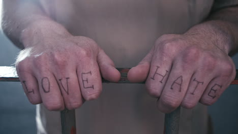 extreme close-up of prison bars as a prisoner walks up to the bars and holds on to them