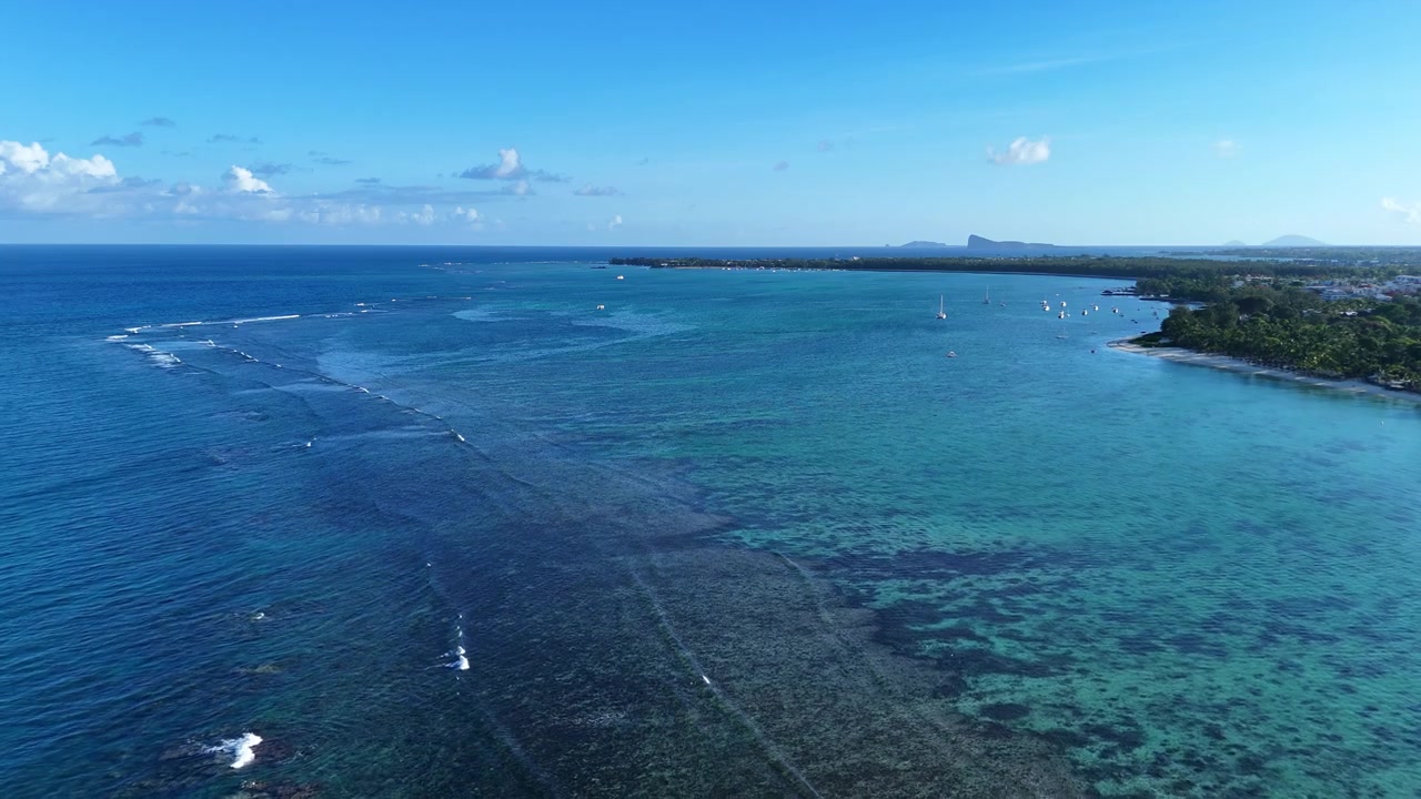 Un drone sorvola una laguna tropicale in direzione dell'isola Le Gabriel a Mauritius.