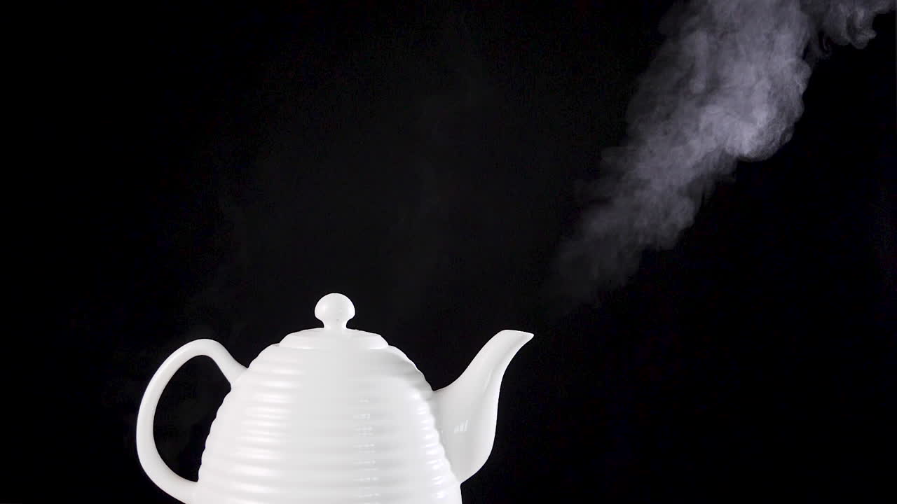 Tea pot on black background with boiling water