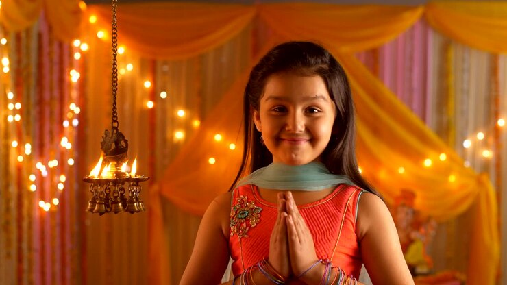 Indian girl with a smiling face looking at diyas - folding hands in namaskar position - Greeting pose