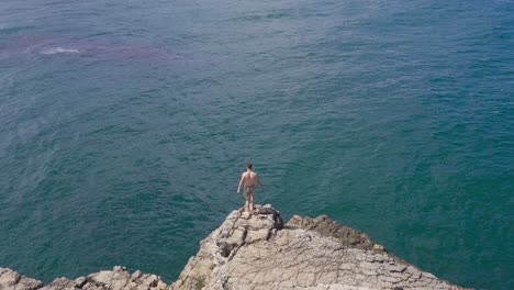 A-young-man-jumping-from-a-cliff-into-the-sea.