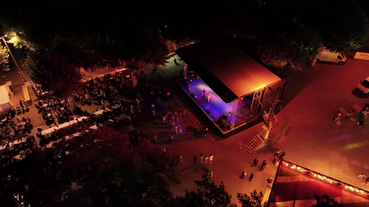 Aerial shot of a small audience sitting at tables at a small festival