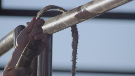 cowboy ties his bull rope to the metal chute to warm it up before a bull riding rodeo