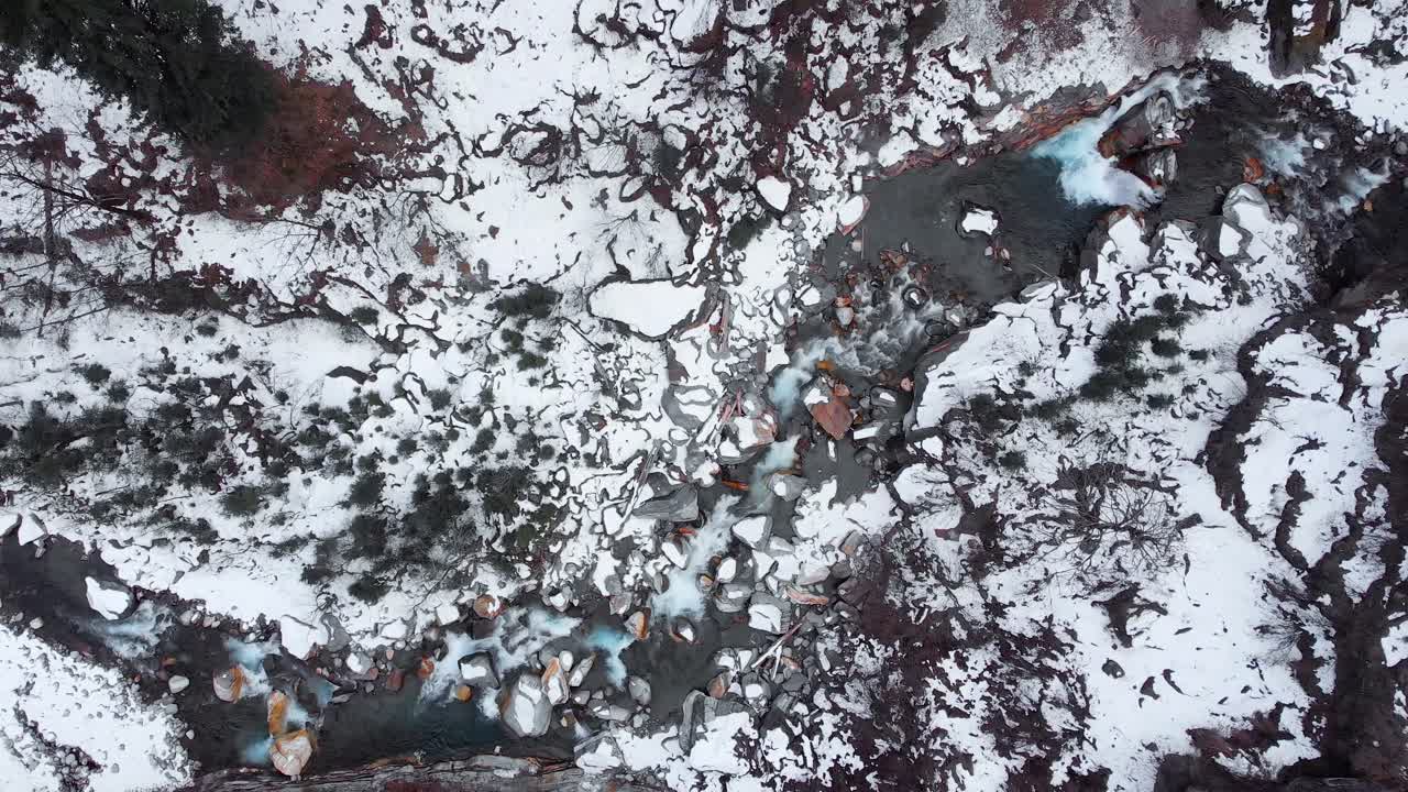 ripresa aerea con ingrandimento lento del fiume glaciale che attraversa la valle coperta di neve durante gli inverni a manali, himachal pradesh, ripresa con un drone in 4k