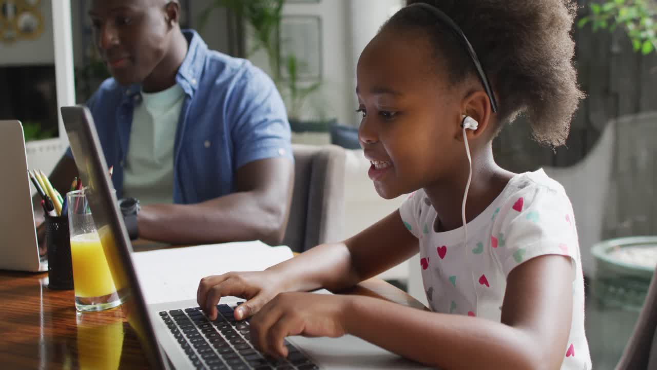 Video of african american father and daughter using laptop and learn