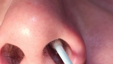 a man inserts a coronavirus test into his nose to perform a self-test for covid-19.