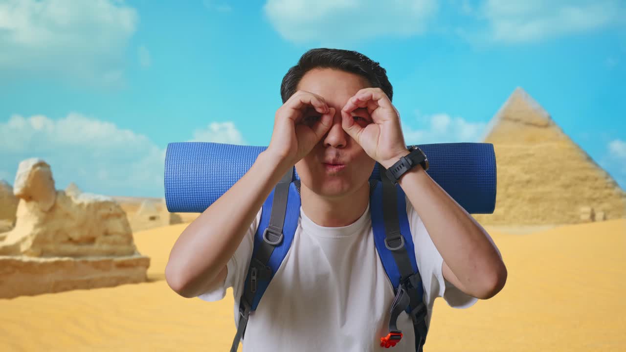 Close Up Of Asian Male Hiker With Mountaineering Backpack Smiling And Making Binoculars Gesture Then Looking Around While Traveling In Pyramid Of Giza