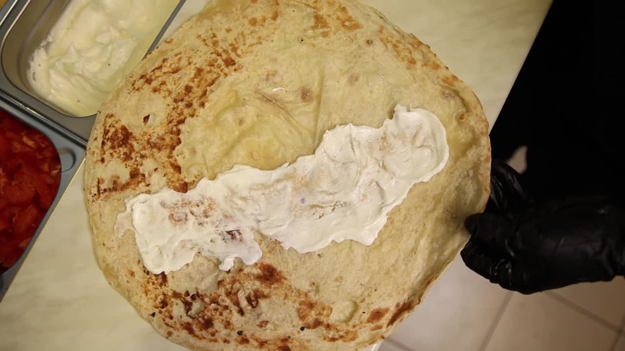 Preparing a wrap with lettuce and sauce