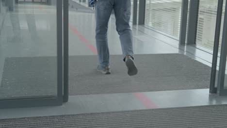 Automatic-sliding-doors-open-as-walking-person-triggers-sensor,-low-angle