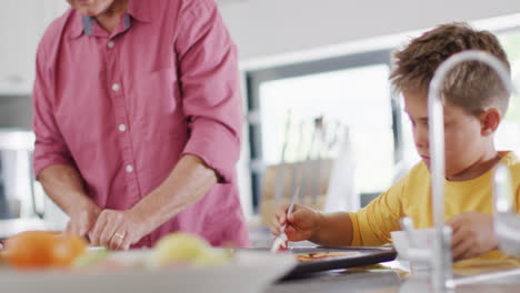 Happy-caucasian-grandfather-and-grandson-making-pizza-in-kitchen,-slow-motion