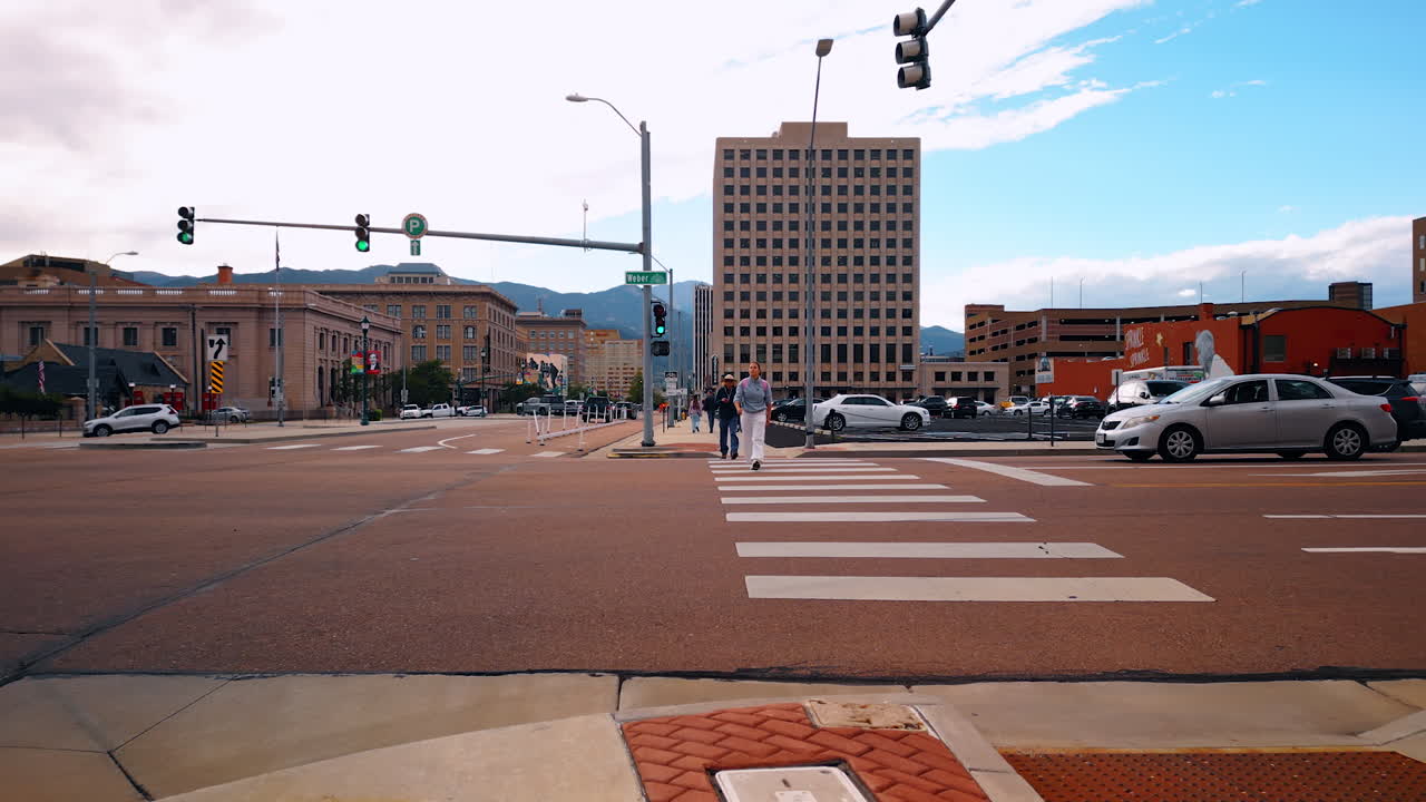 Colorado Springs, USA, 22 July 2025: Distancing from the crossroad with people walking by. View on the street and sidewalk of Colorado Springs, Colorado, USA