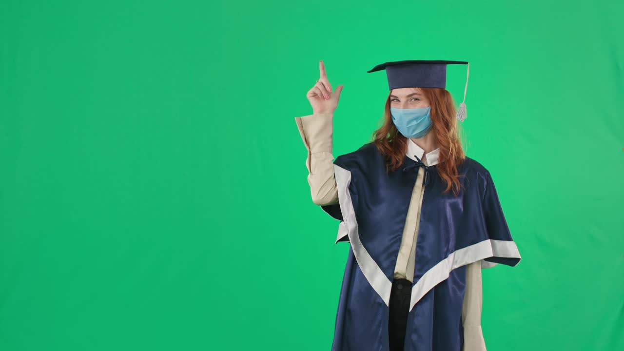 laurea in quarantena, laureato universitario sorridente gioisce al diploma e mostra la mano a lato per l'iscrizione mentre si trova sullo sfondo dello schermo verde