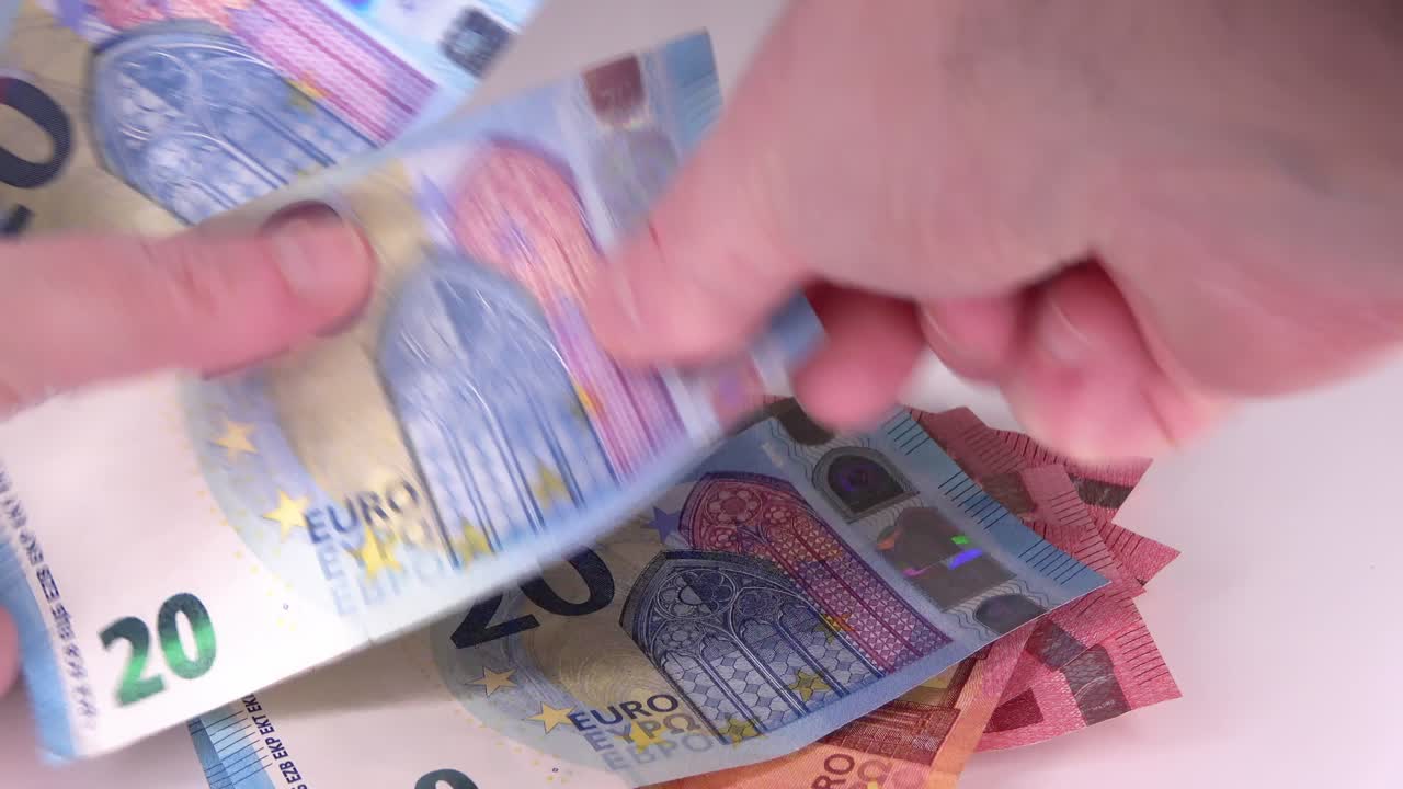 numerosos billetes de 10, 20 y 50 euros contados por manos masculinas en la mesa.