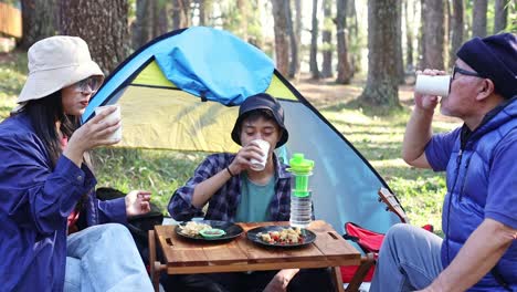 happy asian family camping and drinks coffee together