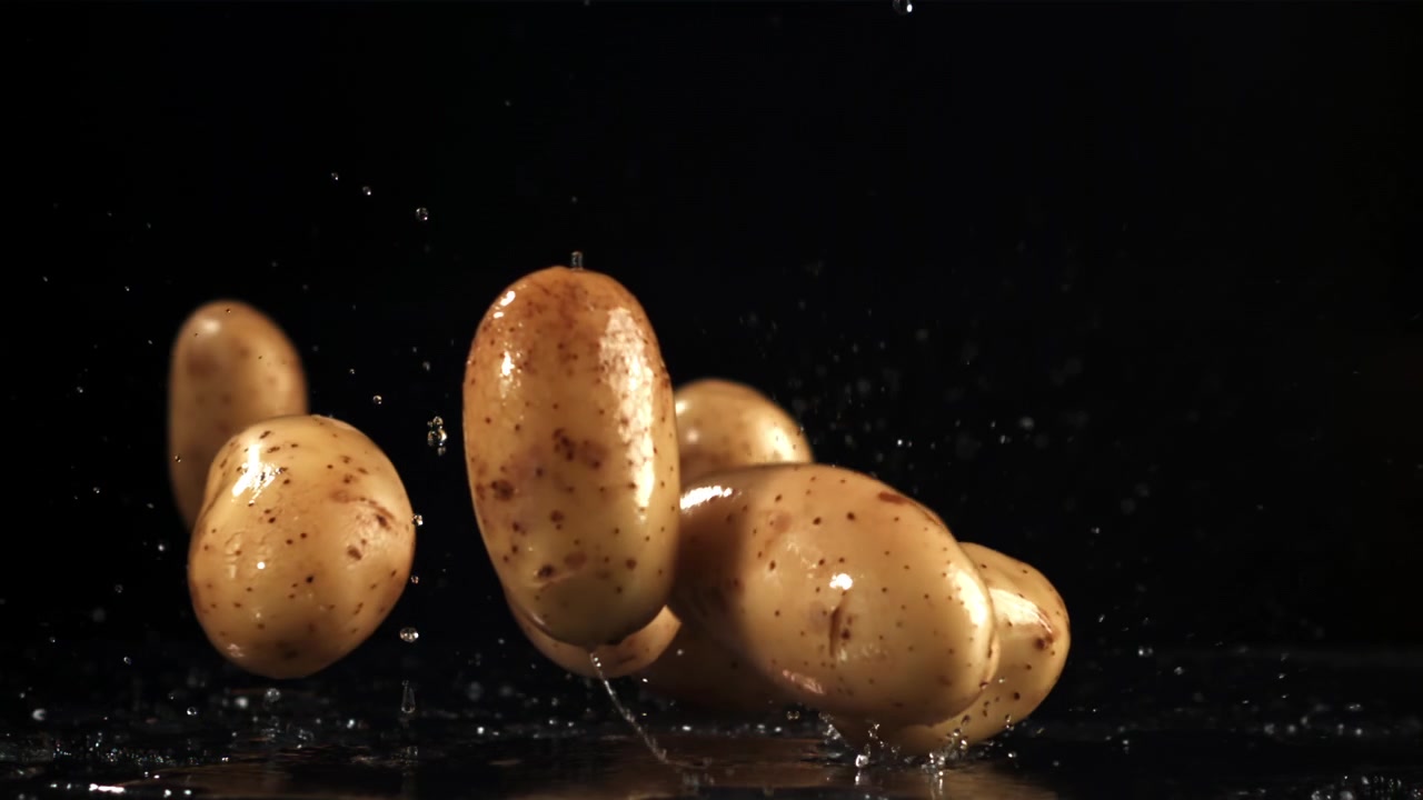 Patate fresche che cadono nell'acqua con schizzi al rallentatore