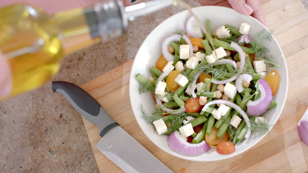 부에서 올리브 오일로 러드를 드레싱하는 두 인종 여성의 손, 복사 공간, 느린 동작