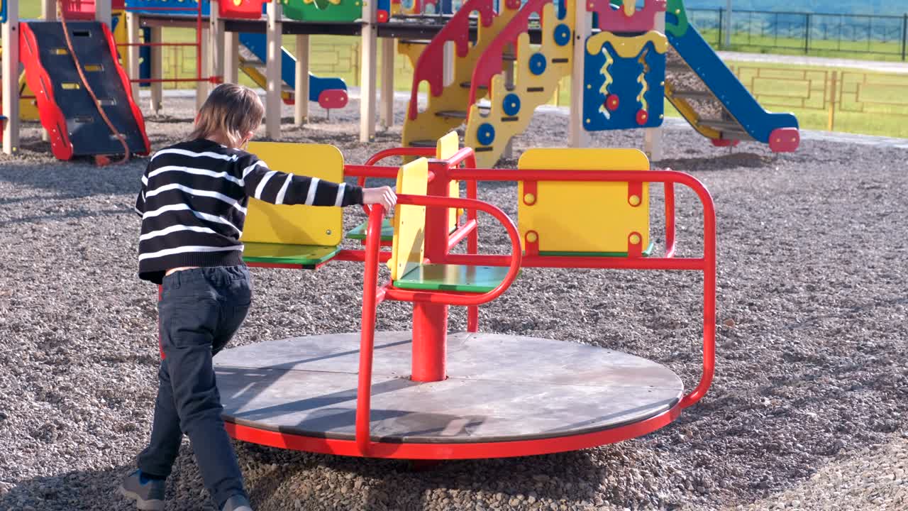 놀이터에서 카루셀을 회전하는 7살 소년.