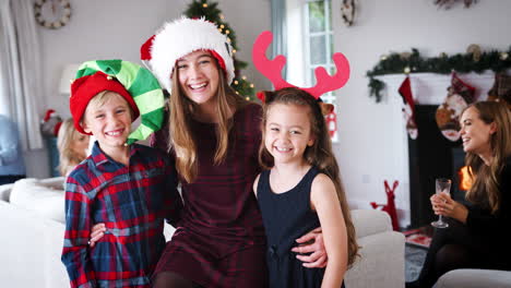 retrato de niños con sombreros de navidad mientras la familia y los amigos de varias generaciones celebran en una fiesta en casa