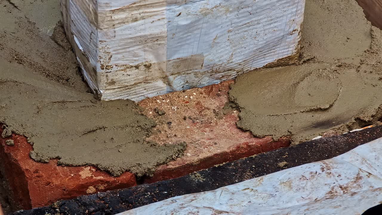 Applicazione di malta su una base di camino in mattoni con una cazzuola, primo piano