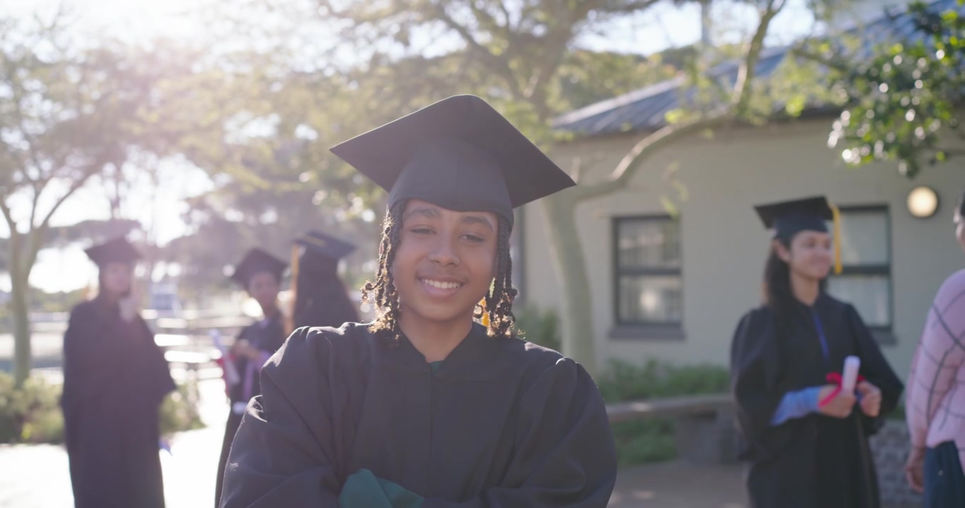 Mujer afroamericana posgraduada con toga levantando y ondeando un diploma con cinta roja, posando en el campus.