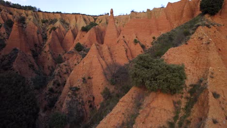 aerial drone flight over las cárcavas de la sierra de ayllón, in madrid during sunny day - growing plants and bush on sandstone hills