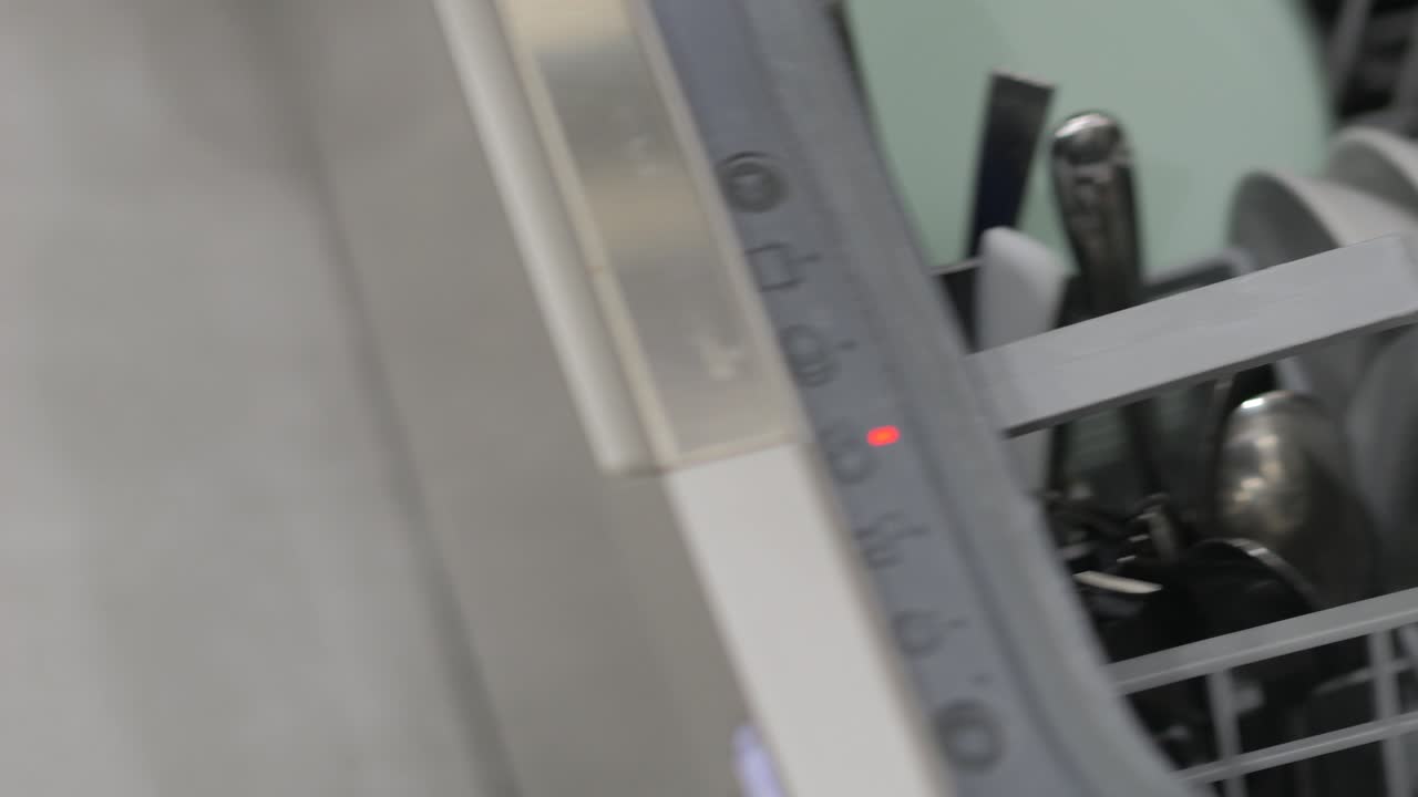 persona poniendo un cuchillo en el lavador de platos y cerrándolo a cámara lenta