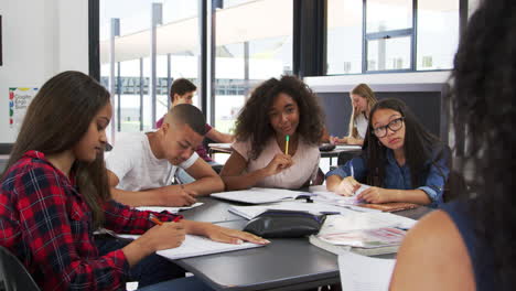 niños de secundaria levantan las manos, el maestro sentado en su escritorio
