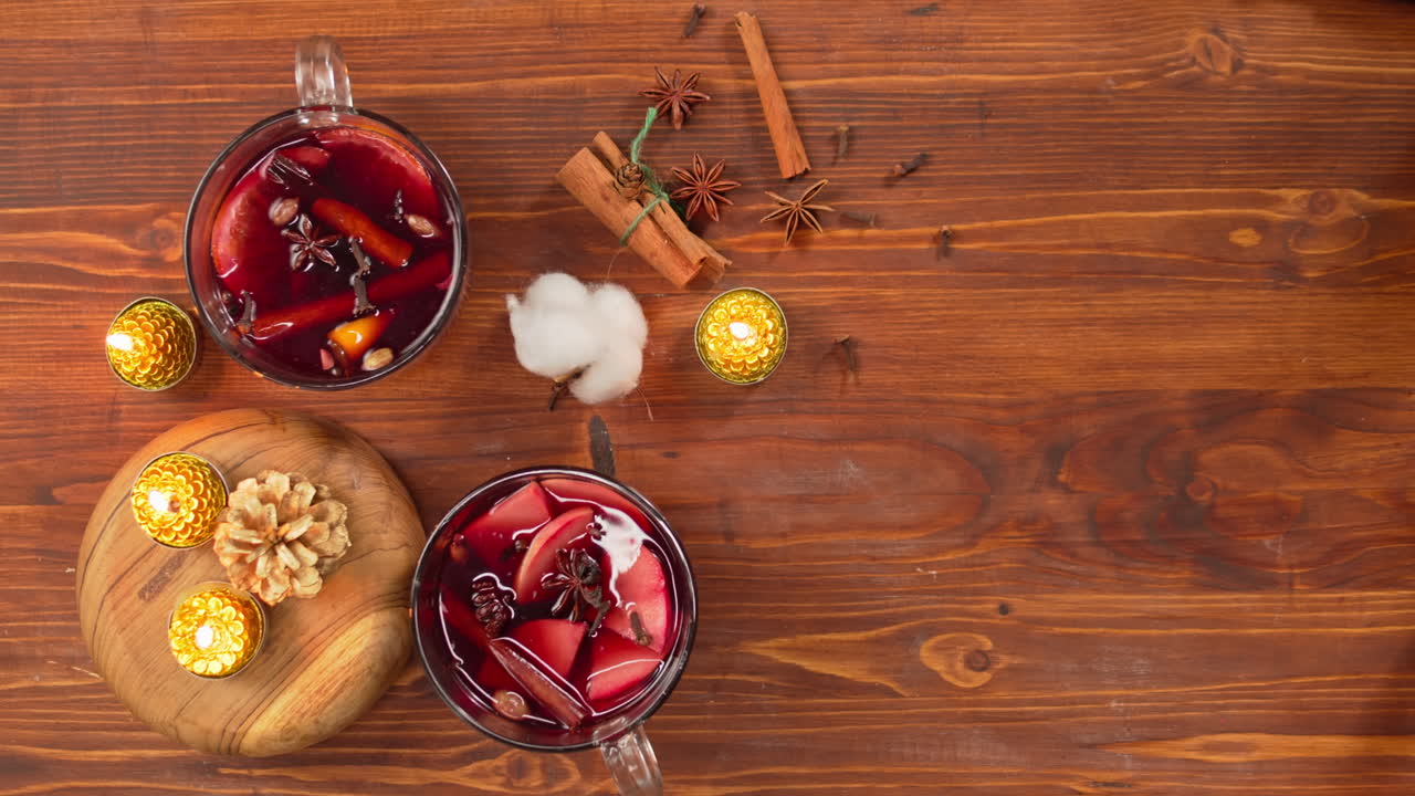 Hände stellen Tassen Glühwein auf einen festlichen Holztisch