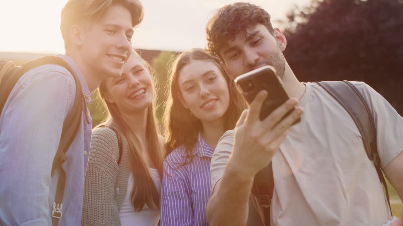 grupo de estudiantes caucásicos tomando selfies fuera del campus de la universidad.