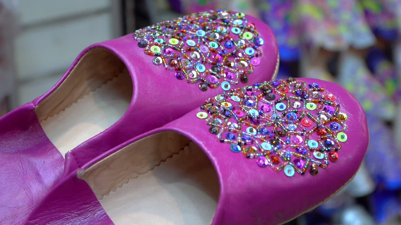 스타일리시한 분홍색 벨가 가죽 신발은 마라케시의 활기찬 오래된 메디나 시장에서 모로코 공예품을 선보이고 있습니다.